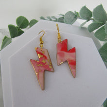 Load image into Gallery viewer, Pink lightning bolt earrings with gold accents on a white card with green leaves in the background