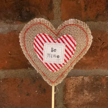 Load image into Gallery viewer, Heart-shaped fabric decoration with 'Be Mine' text against a brick wall.