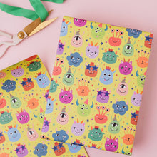 Load image into Gallery viewer, Colorful monster-patterned paper with scissors on a pink background
