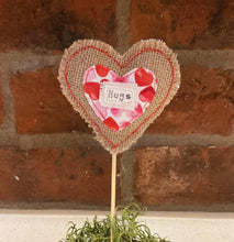 Load image into Gallery viewer, Heart-shaped decorative item with 'Hugs' text against a brick wall background

