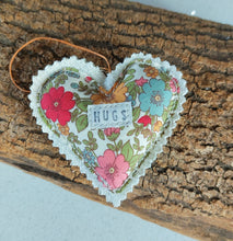 Load image into Gallery viewer, Heart-shaped floral ornament with 'HUGS' text on a wooden surface

