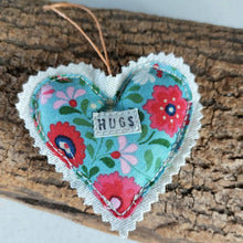 Load image into Gallery viewer, Floral heart-shaped fabric ornament with 'HUGS' label on a wooden surface
