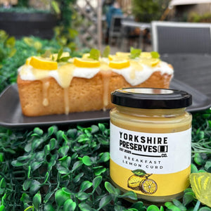 Loaf cake with lemon curd and cream on a tray, accompanied by a jar of Yorkshire Preserves lemon curd.