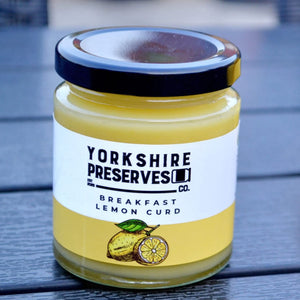 Jar of Yorkshire Preserves lemon curd with lemons on a wooden surface
