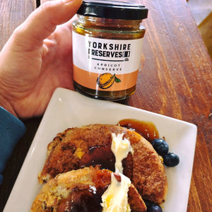 Yorkshire Reserves apricot conserve jar with pancakes and blueberries on a plate.