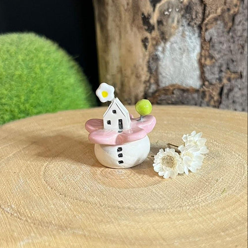 Small decorative item resembling a fairy house with pink roof on a wooden surface.