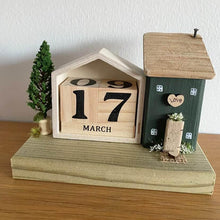 Load image into Gallery viewer, Wooden house-shaped calendar with decorative elements on a wooden surface
