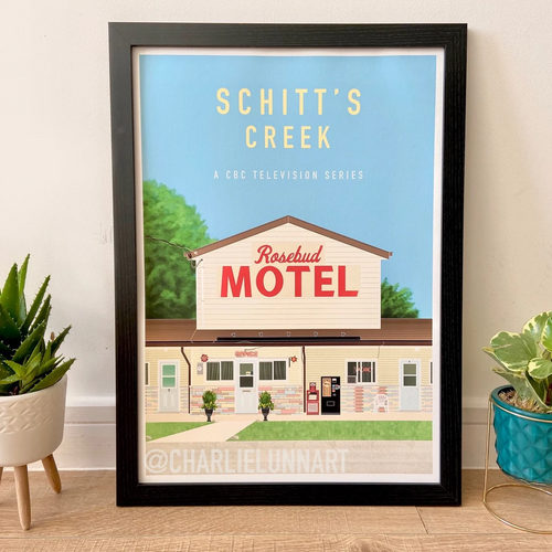 Framed poster of Rosebud Motel from 'Schitt's Creek' with plants on either side.